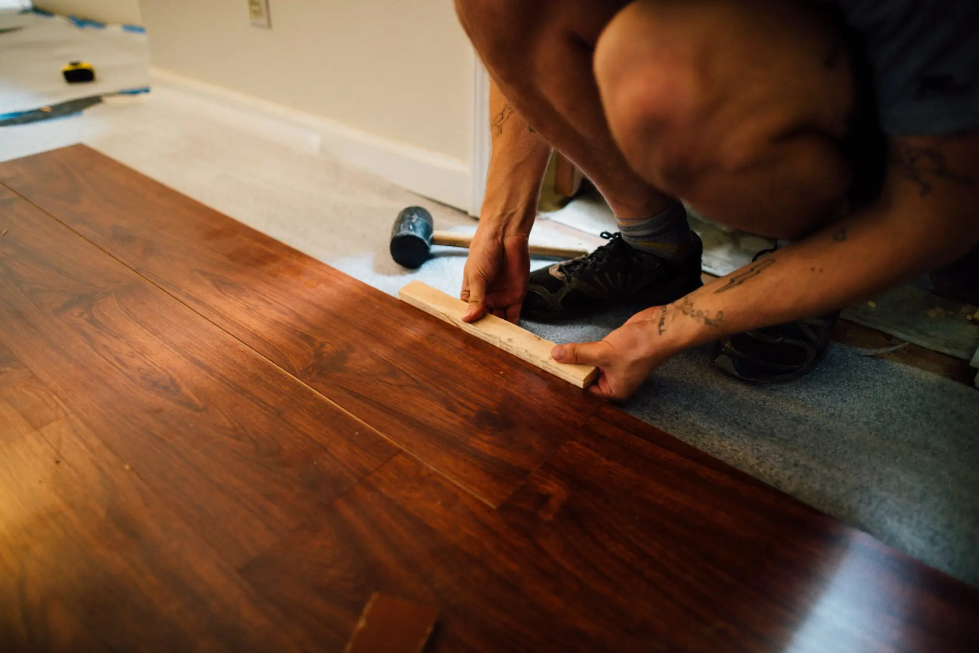 Installer fitting timber floor planks by hand
