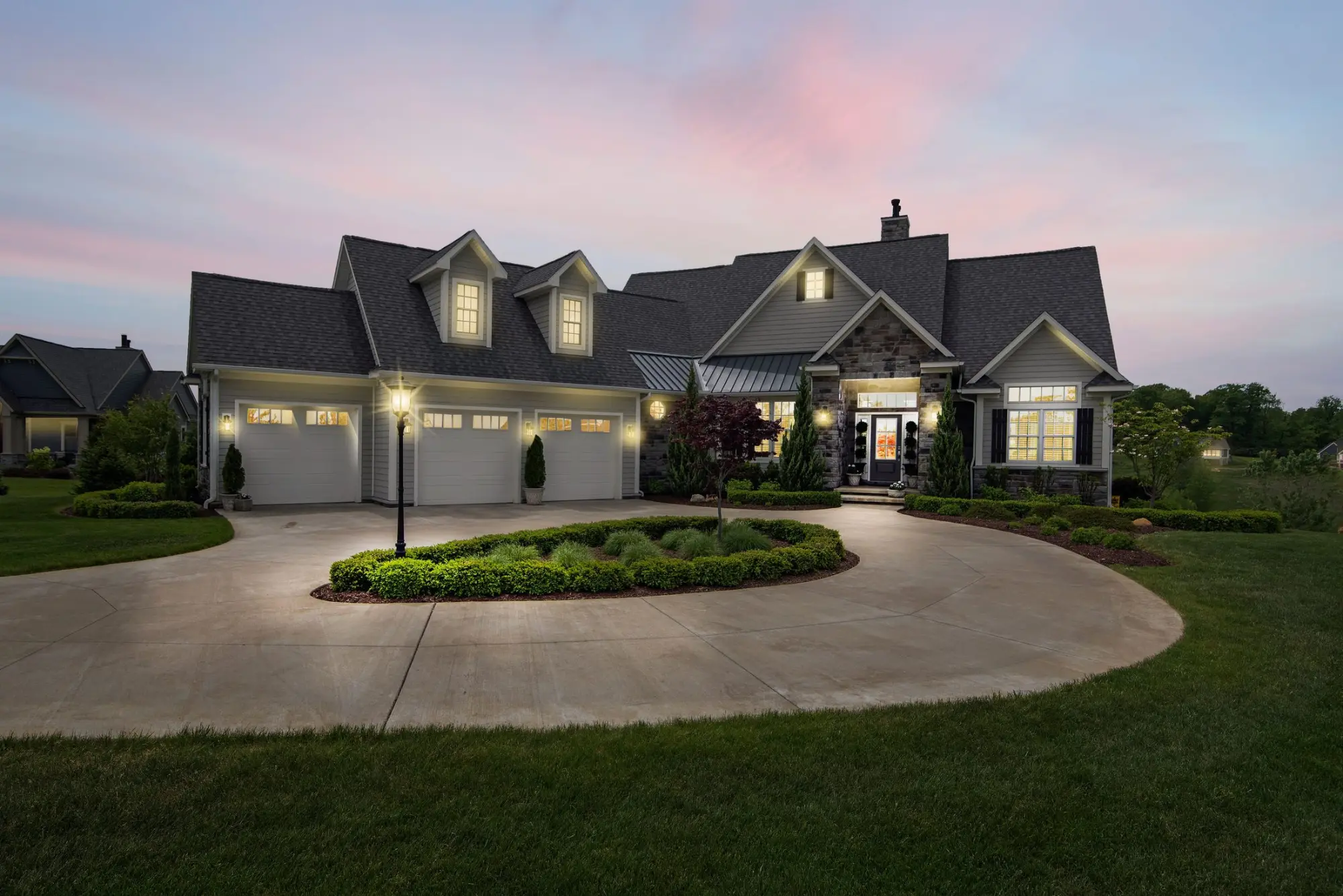 Gabled family home with stone accents and a circular drive at dusk