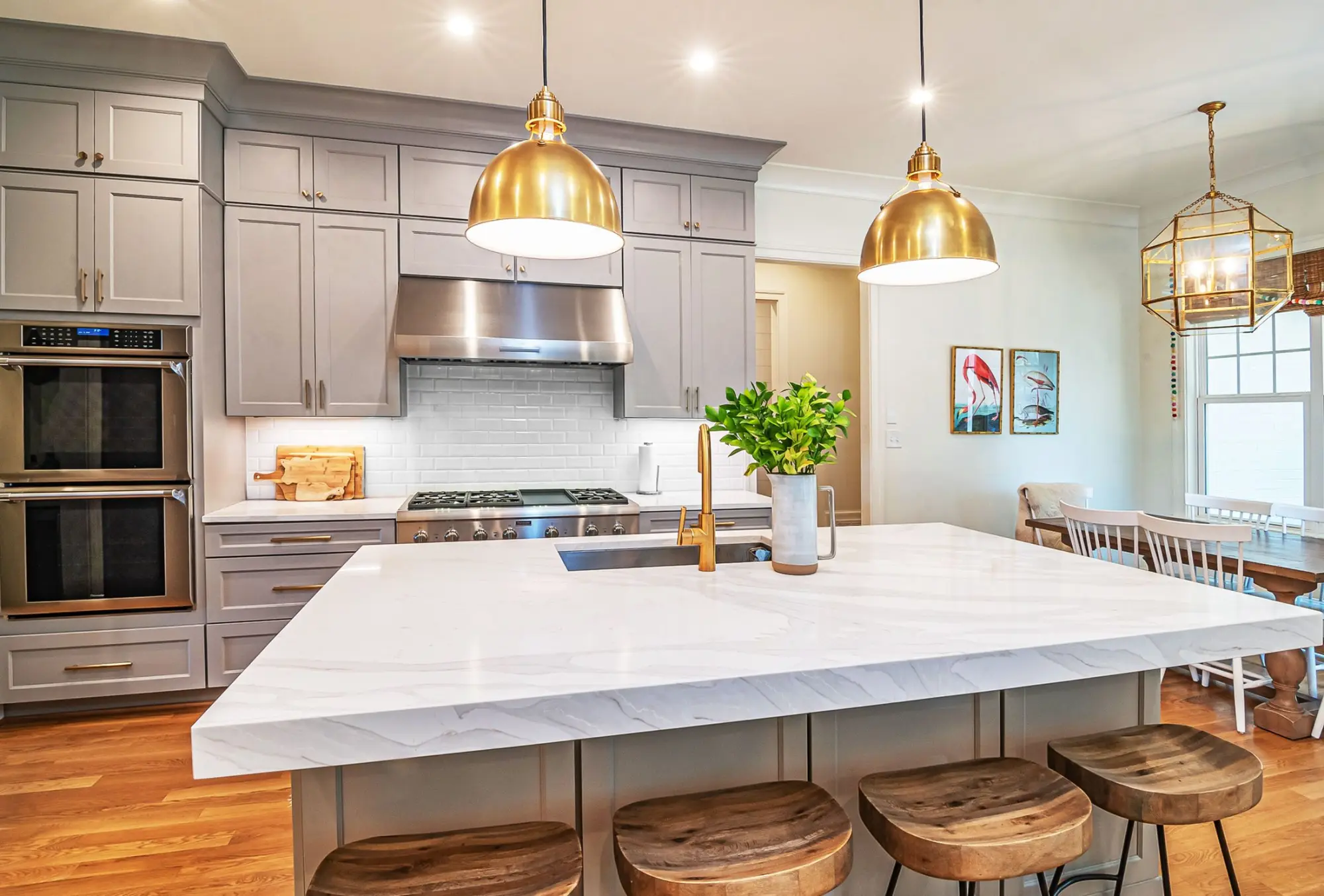 Kitchen with a white marble island, brass dome pendants and timber counter stools