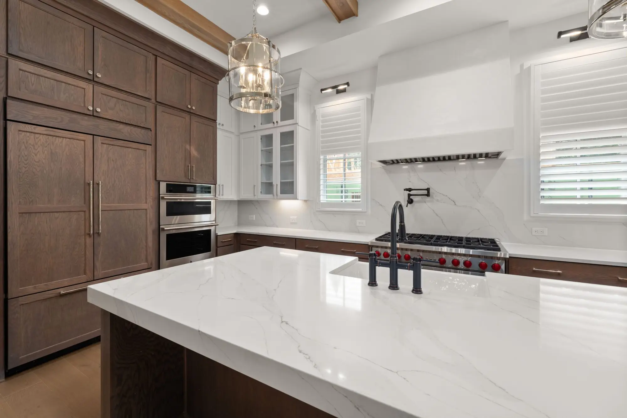 Kitchen with a white marble island, dark timber cabinetry and a lantern pendant