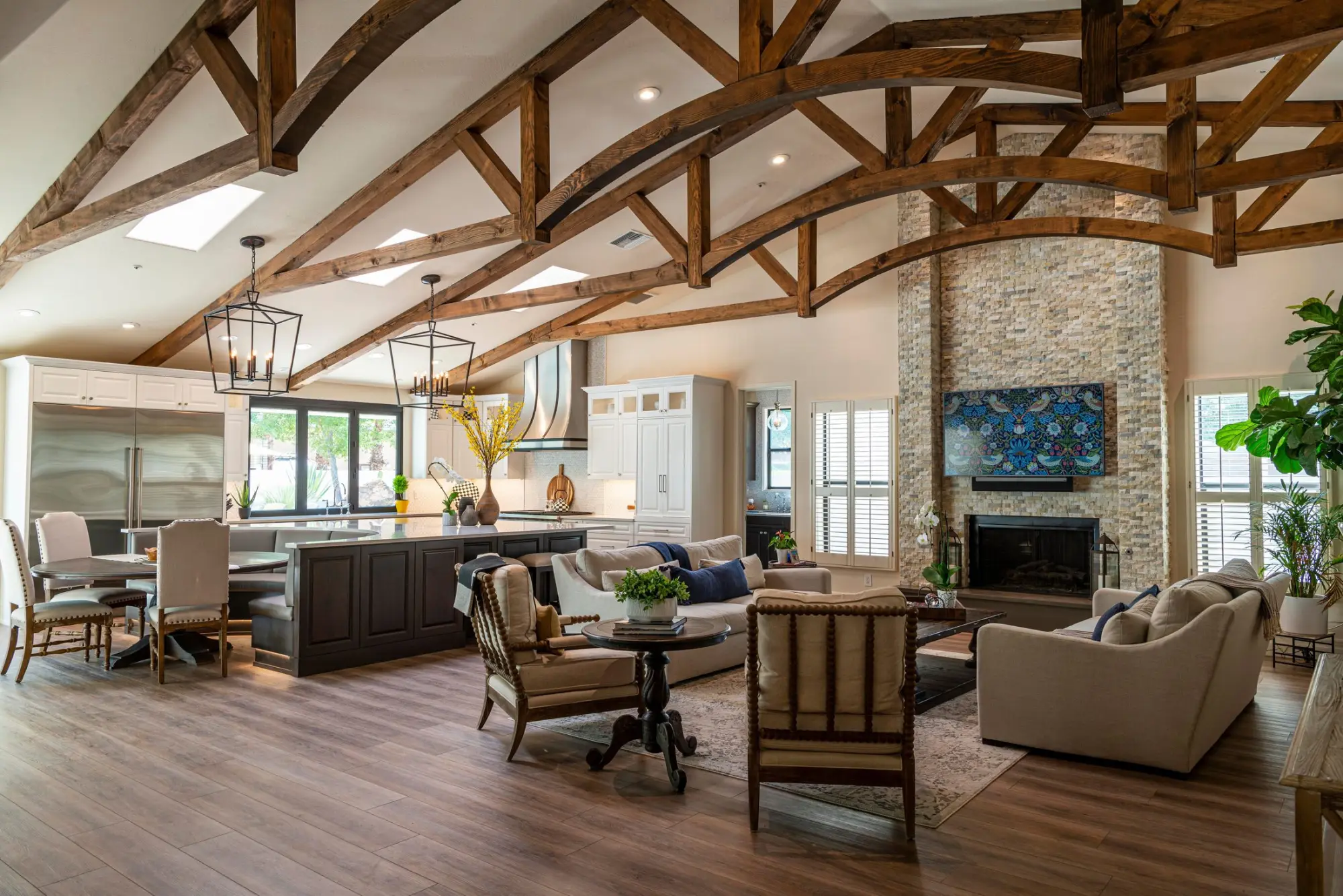 Open great room beneath exposed timber trusses, with living and dining areas together