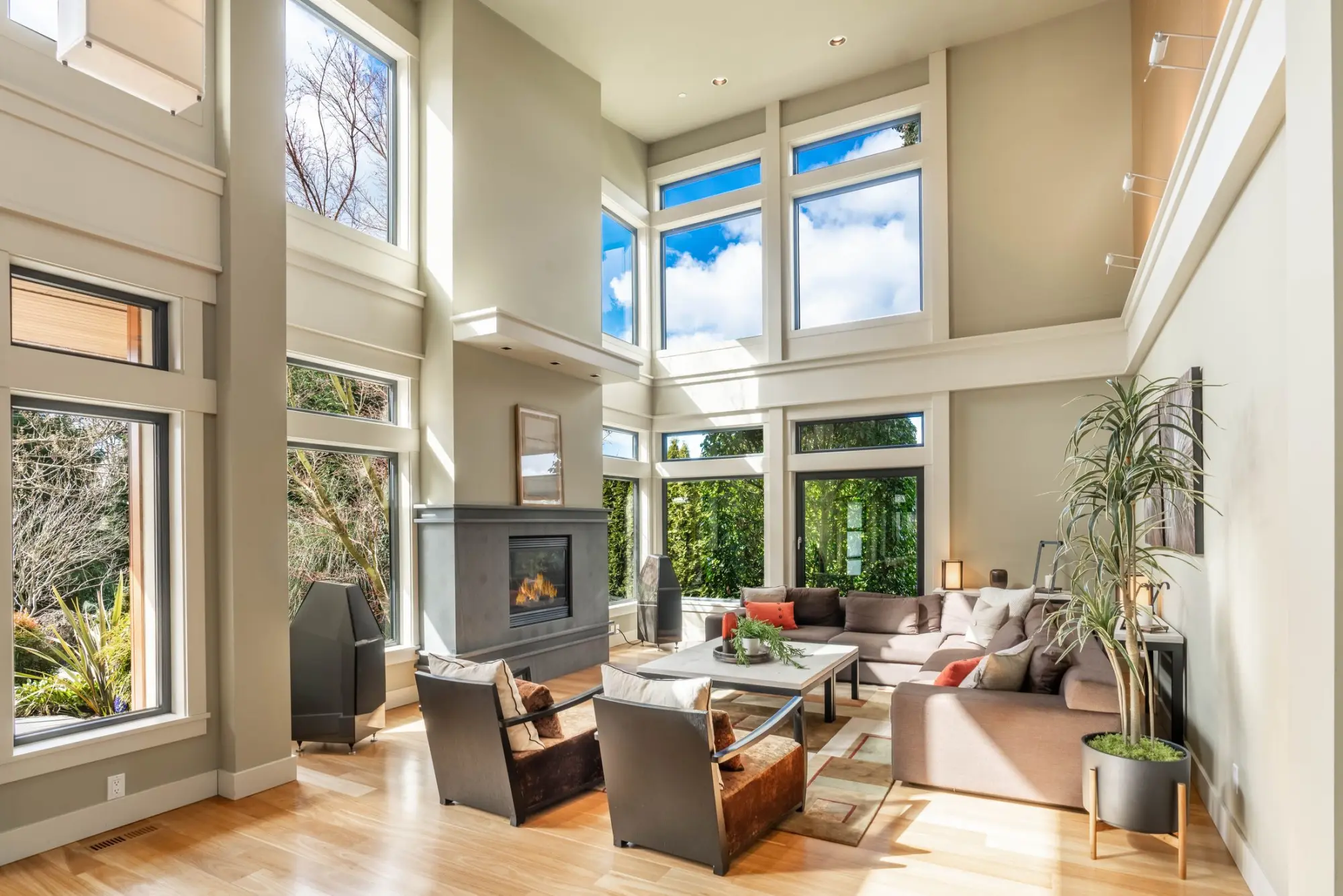 Two-storey living room with tall windows, a fireplace and low sofas