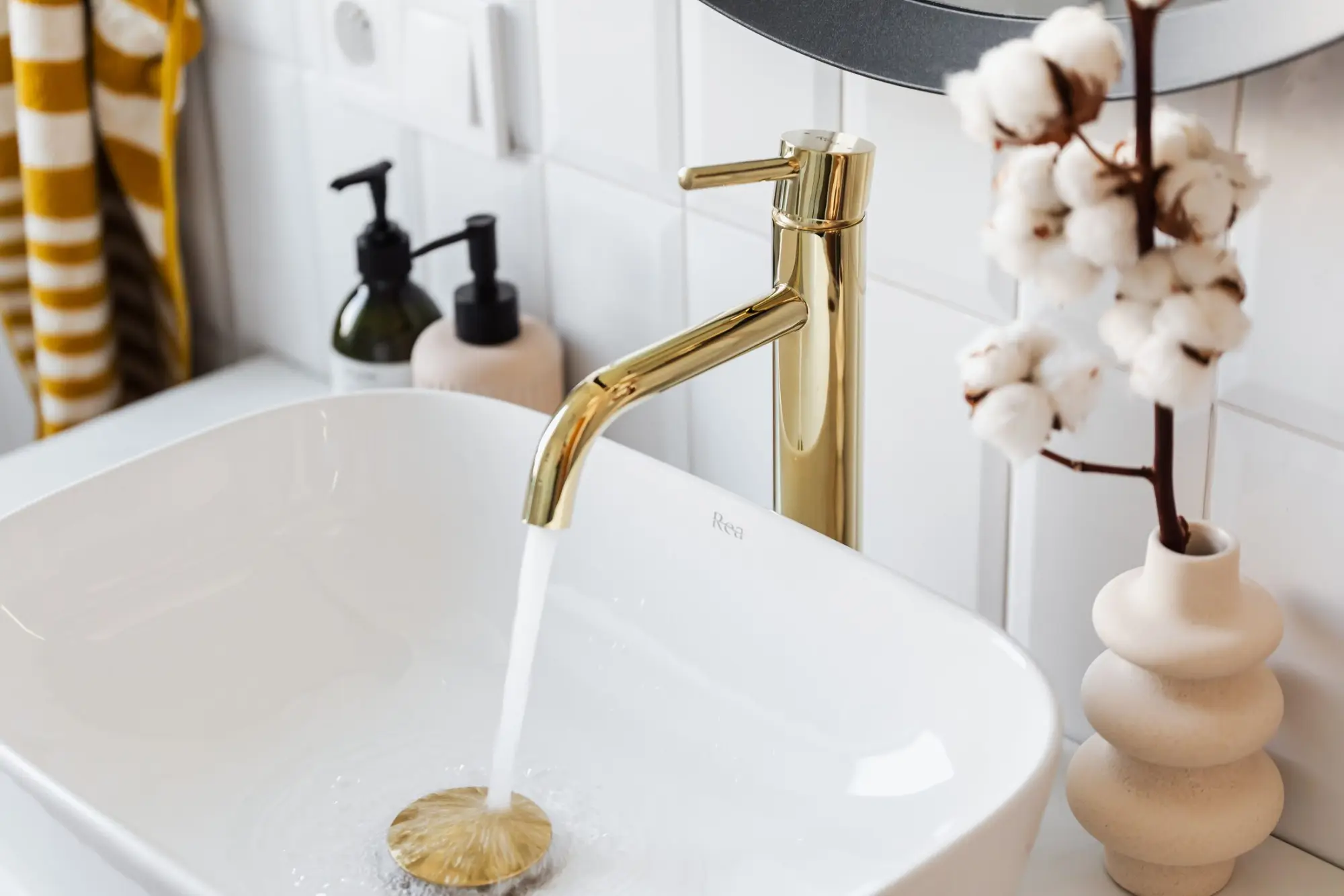 Brushed brass faucet running into a white vessel sink